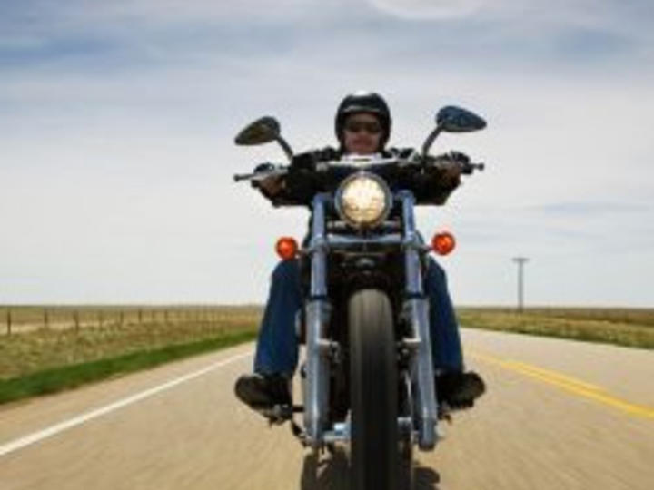 A man riding a motorcycle towards the camera on a Georgia country road.