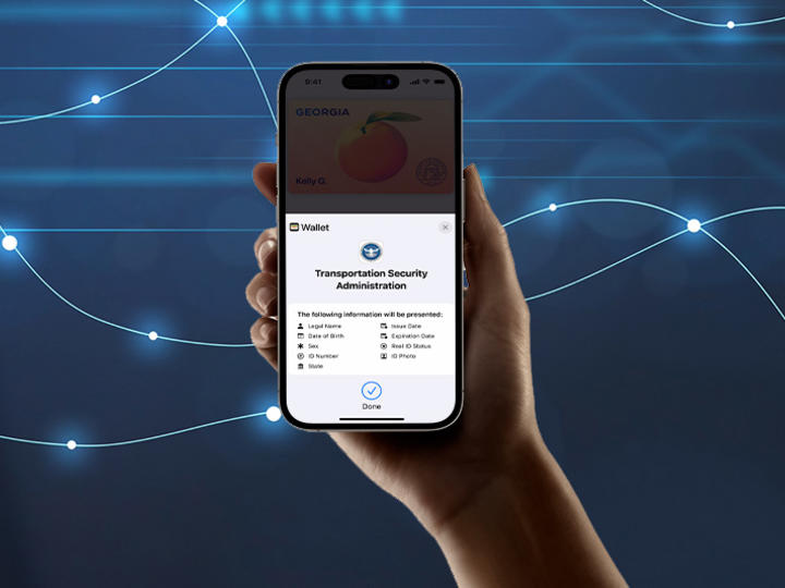 Hand holding a phone showing secure connection to a device used by the Transportation Security Administration (TSA) with a blue digital background.