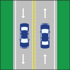 A two-way street with yellow center lines, one solid and one dashed