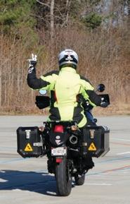 Motorcyclist holding up their left arm with two fingers extended