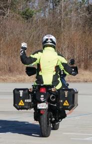 Motorcyclist with their left arm raised in a fist