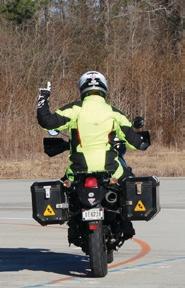 Motorcyclist holding up their left arm with one finger extended
