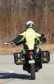 Motorcyclist with their left arm extended and their open palm towards the ground