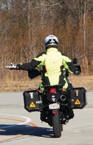 Motorcyclist with their left arm extended and their open palm facing upward