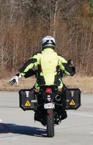 Motorcyclist with their left arm extended and their open palm facing the rear