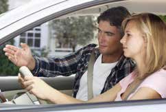 A father provides direction from the passenger seat while his daughter drives