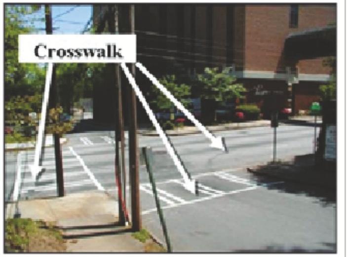 A four-way intersection with three crosswalks marked by white painted lines and one unmarked.