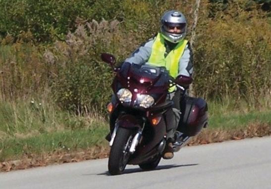 Motorcyclist is wearing a bright yellow, reflective vest