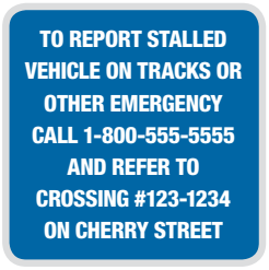 Blue, square sign reads "To report stalled vehicle on tracks or other emergency call 1-800-555-5555 and refer to crossing number 123-1234 on Cherry Street"