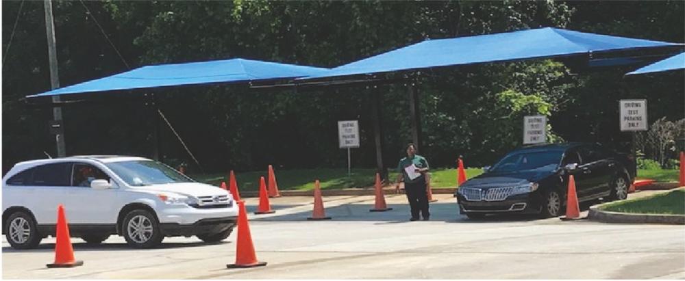 Driving test in progress, orange cones on the road with an instructor directing cars