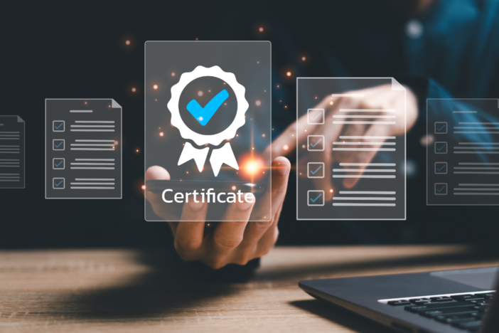 Hands in front of a laptop pointing at digital displays of forms to include a Certificate confirmation icon.
